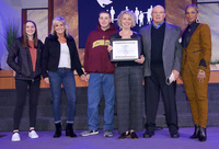 Heather Cox-Coleman (right) of the World Arts Foundation presents the Award to Karen Barker (third from right). With them are, left to right: granddaughter Hailey Harwood, daughter Kimberly Harwood, grandson A.J. Harwood and husband Terry Barker