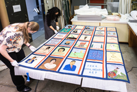 OHS collections staff assess the Afro-American Heritage Bicentennial Commemorative Quilt after conservation in December 2021. Oregon Historical Society photograph.